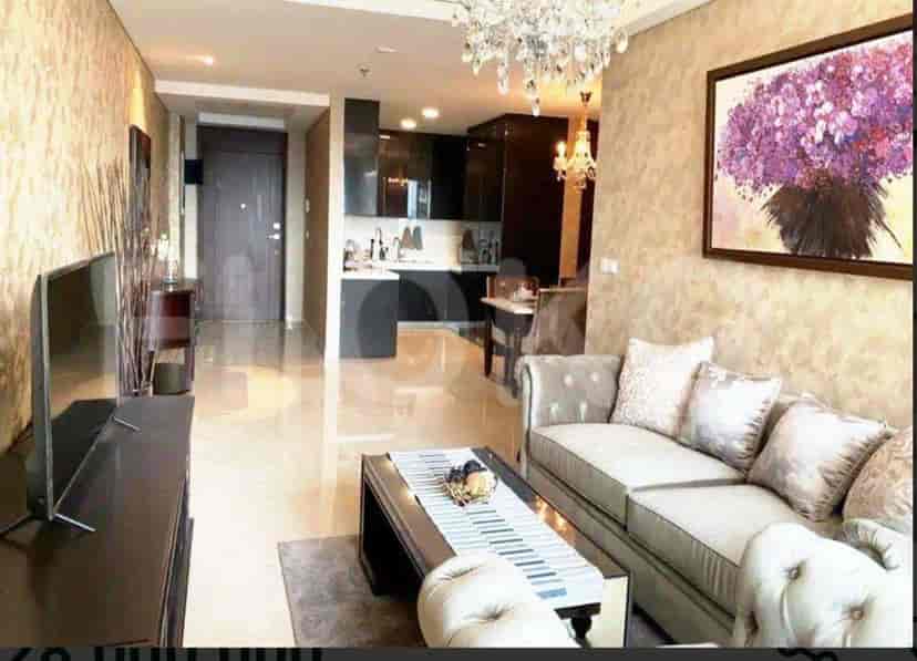 A modern living space with an open kitchen, a grey sofa, and a TV.