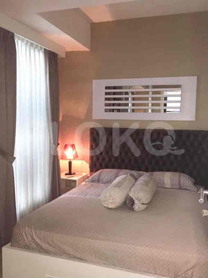 A cozy bedroom featuring a bed, a nightstand with a lamp, and a window with curtains.