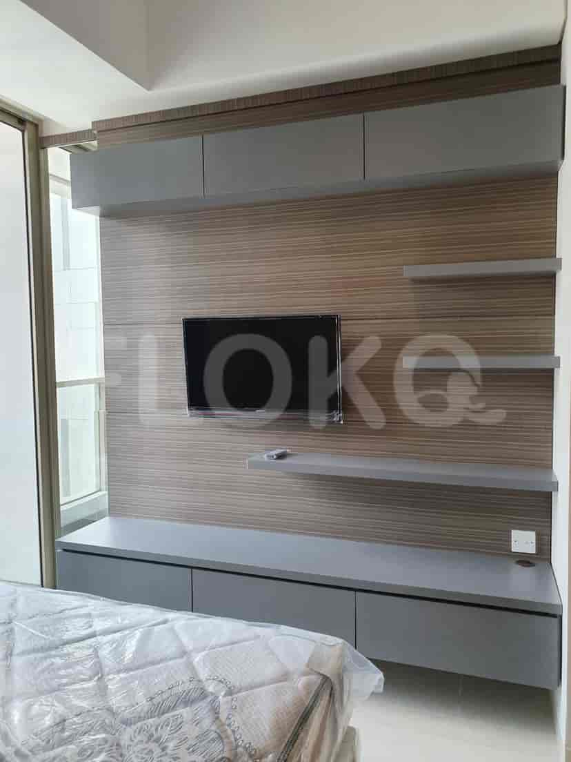 Bedroom featuring a TV mounted on a wooden panel, a bed, and a window.