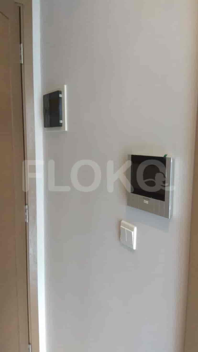 The entrance of a modern apartment, featuring a door, intercom, and light switch.