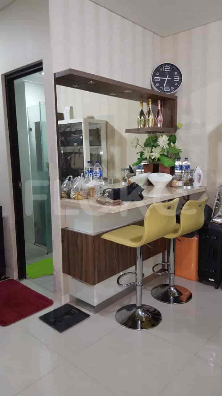 A kitchen area with a bar counter, stools, and a clock on the wall.