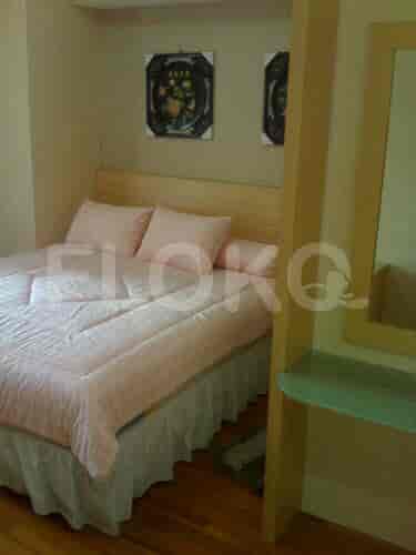 A bedroom with a double bed, light-colored wooden headboard, and two decorative paintings.
