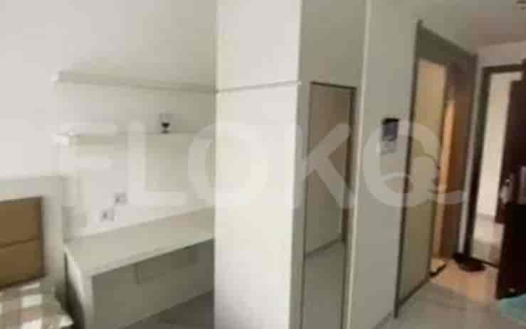A bedroom with a desk area, a large mirror, and a door.
