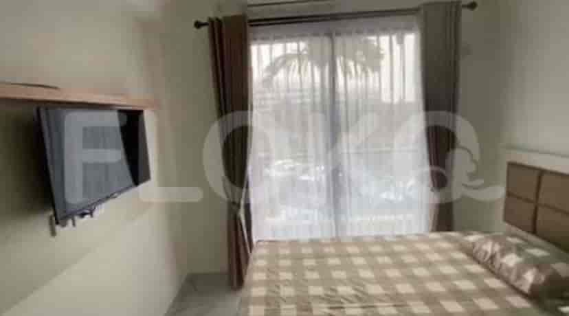 A bedroom with a bed, TV, and a window.