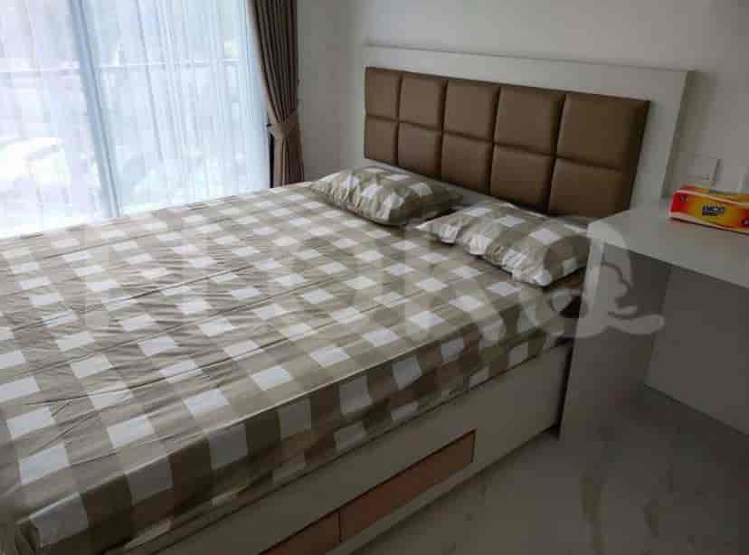 A bedroom with a queen bed, pillows and a large window.