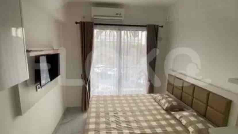 A bedroom with a queen bed, wall-mounted TV, and a large window.