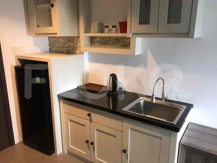 A close-up view of a kitchenette, highlighting the sink, cabinets, mini-fridge, and various kitchen supplies.