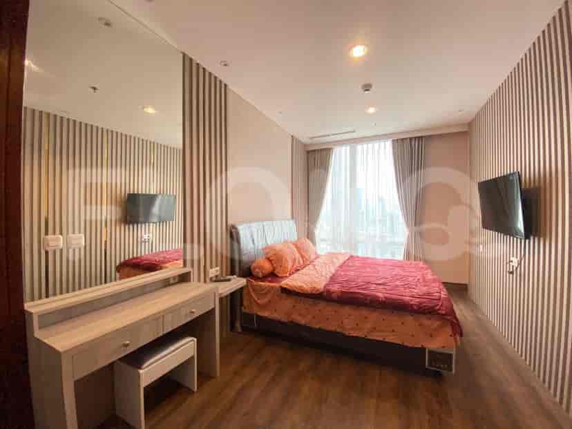 A sophisticated bedroom featuring a king bed, a vanity area, and a wall-mounted TV.