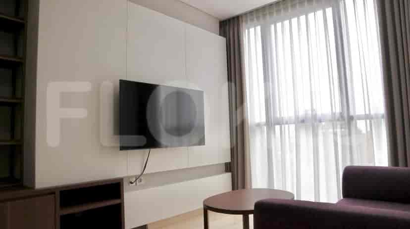Modern living room with a wall-mounted TV, built-in storage, and a round coffee table.