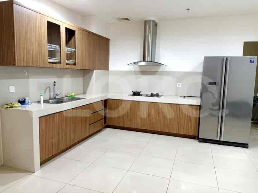 A modern kitchen with a white island, wooden cabinetry, and a stainless steel refrigerator.