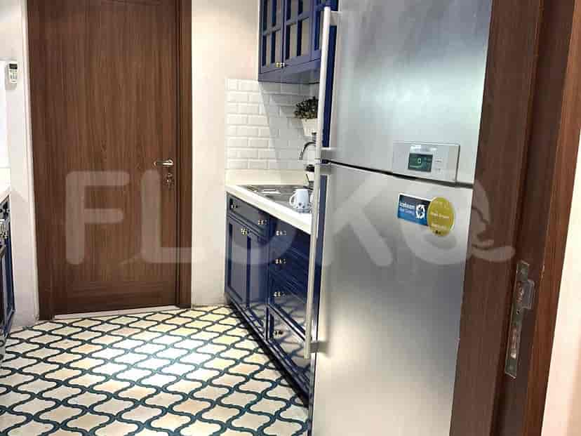 A modern kitchen with blue cabinets, a stainless steel refrigerator, and patterned tiled flooring.