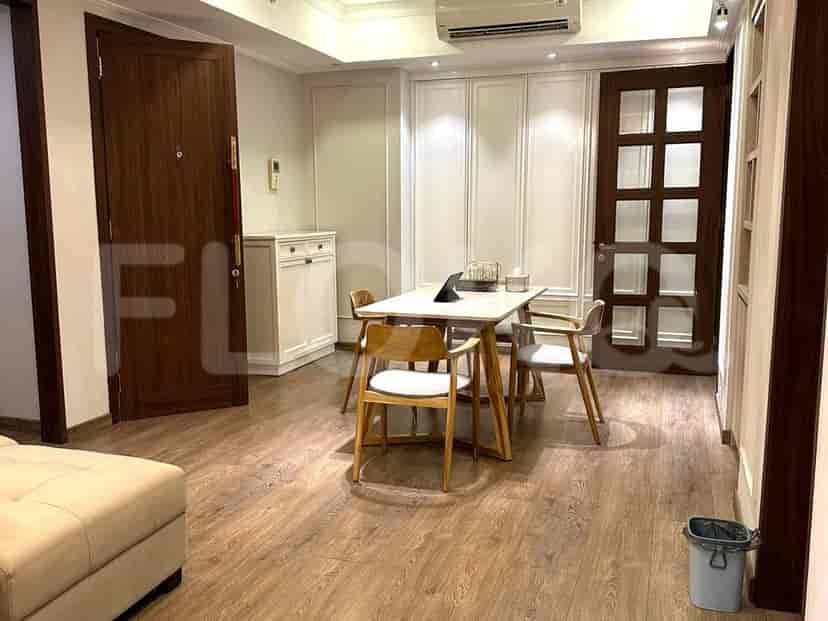 The dining area of an apartment with a table and chairs, along with an entrance door and white paneling.