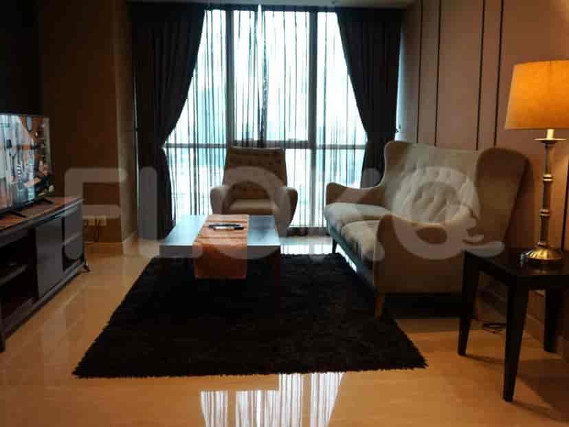 Ruang tamu dengan sofa krem, kursi lengan, meja kopi, dan jendela besar dengan gorden.