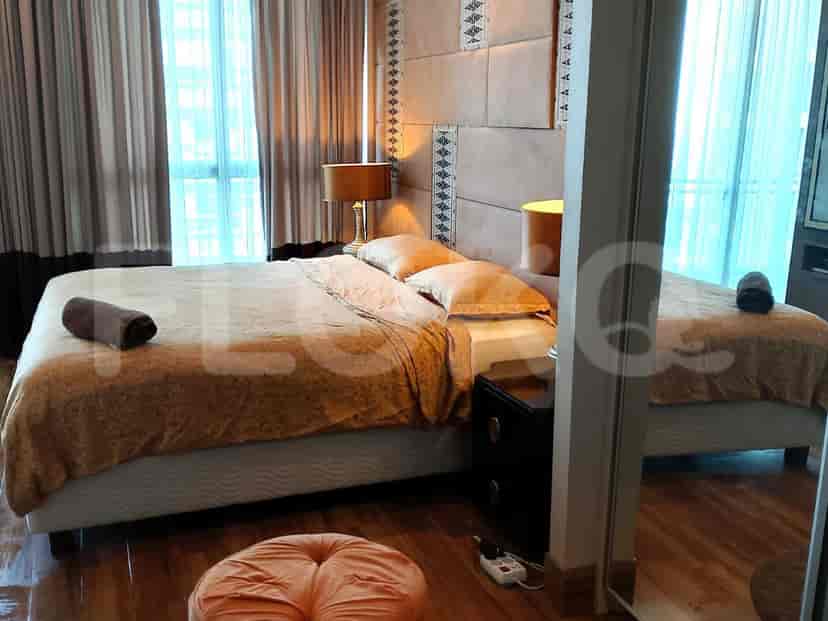 Kamar tidur dengan tempat tidur, meja samping tempat tidur, dan jendela besar.