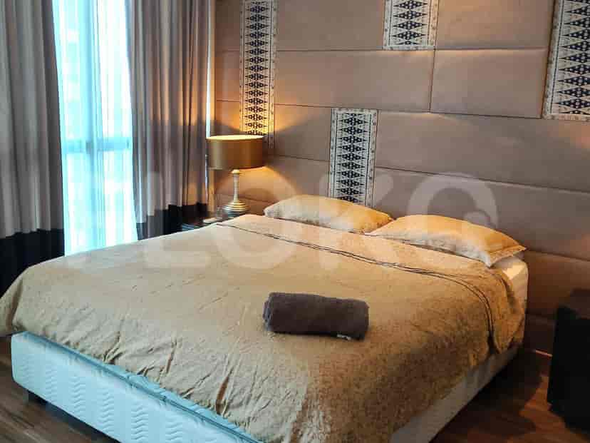 Kamar tidur modern dengan tempat tidur besar, lampu samping tempat tidur, dan panel dinding bermotif.