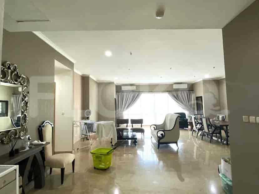 A spacious living room with a large window, seating area, and dining table.