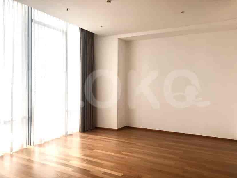 Bedroom with light wooden flooring, white walls, and a window with a blind.