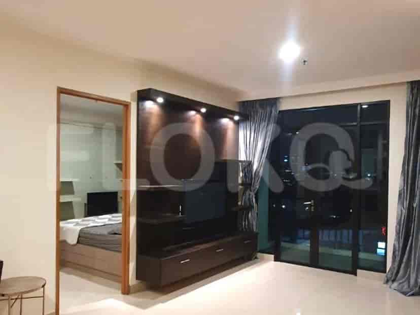 A living room with a television and a connected bedroom.