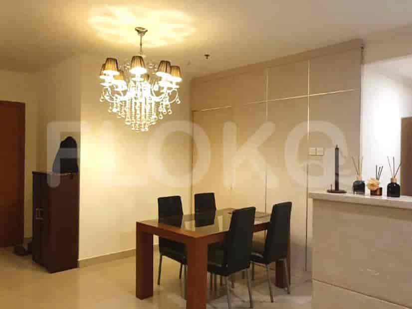 An elegant dining area with a chandelier, a glass-top dining table, and four black chairs.