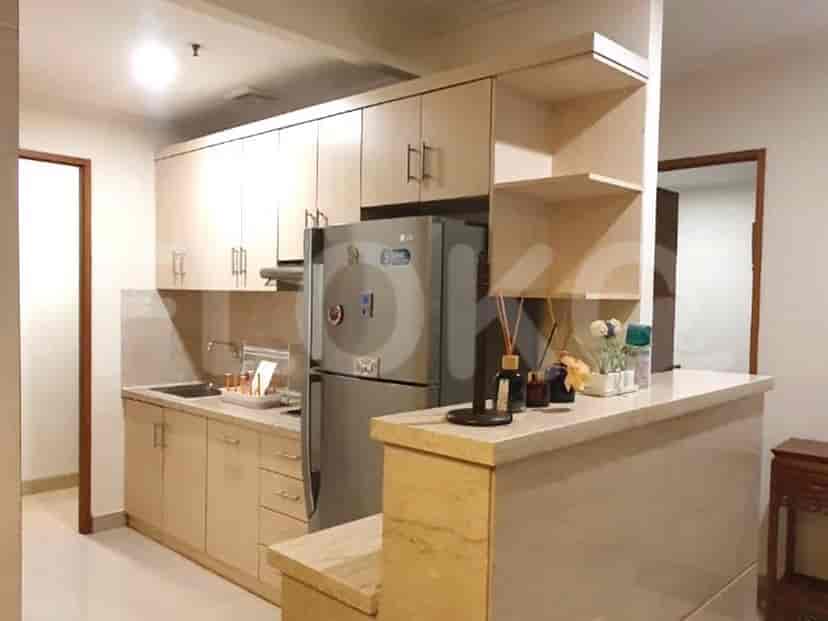 A modern kitchen with light wood cabinetry, stainless steel appliances, and a breakfast bar.