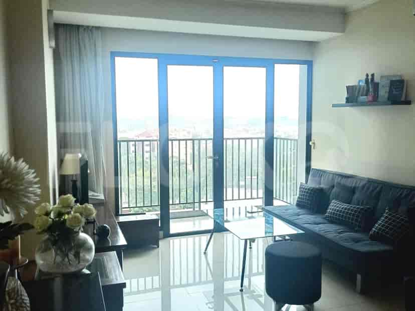 Ruang tamu modern dengan sofa abu-abu, meja kopi kaca, dan akses balkon.