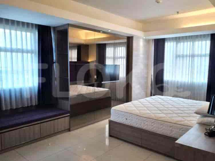 A spacious bedroom with a bed and a built-in desk with an adjoining window.