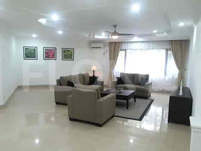 A spacious living room with an L-shaped grey sofa, artwork, and large windows with sheer curtains.