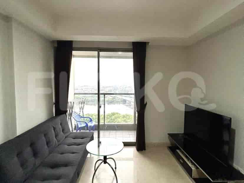 A living room with a grey sofa, round glass table, and a TV unit.