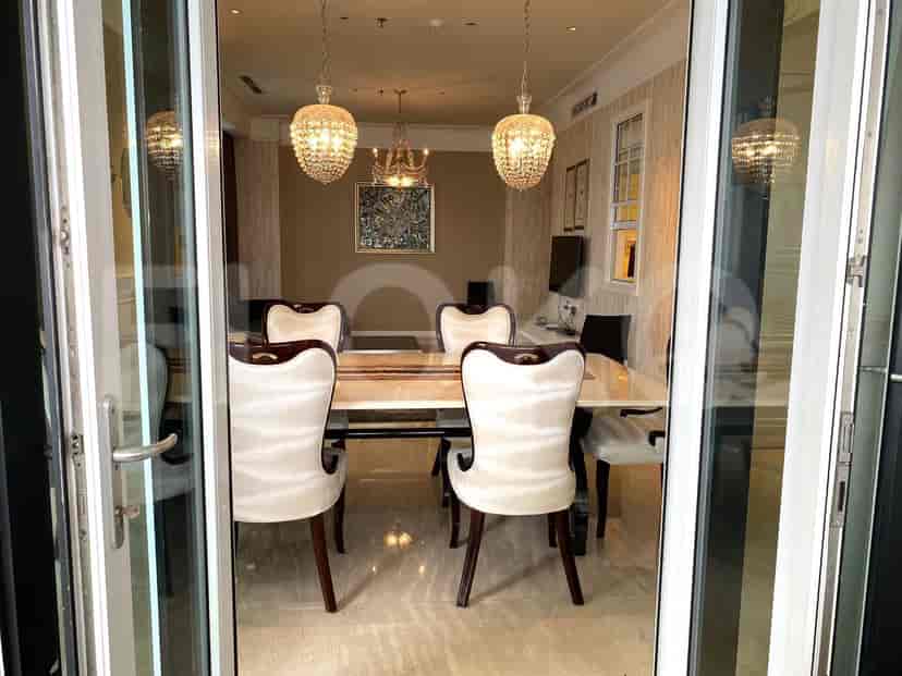 View of a dining room through glass doors with dining table and chandelier.