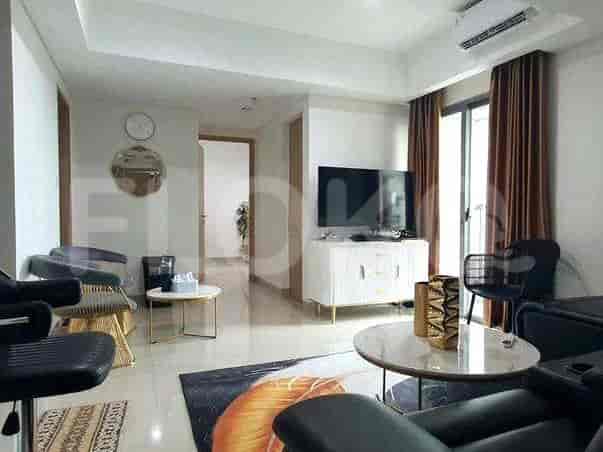 Another view of the living room with a TV, side chairs, and access to a balcony.