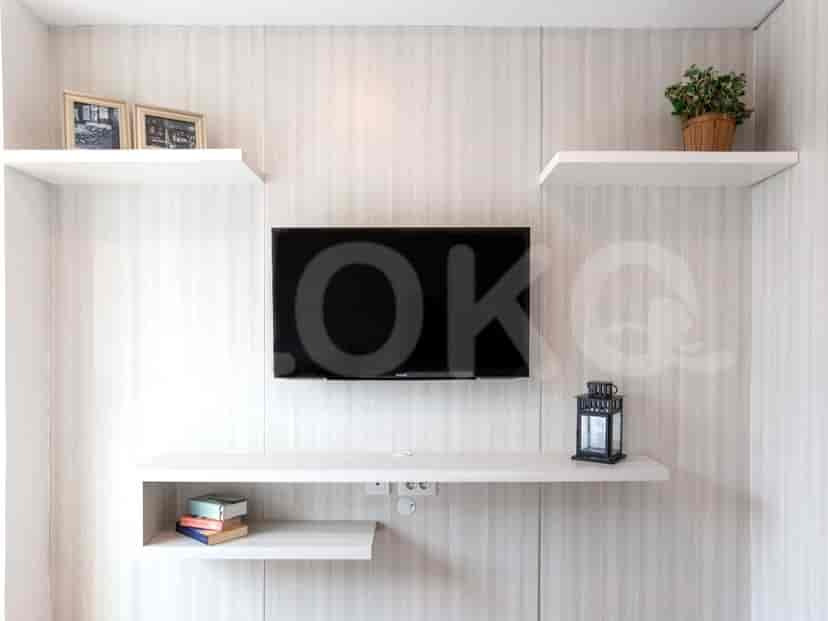 A wall with a TV, shelves, and decor.