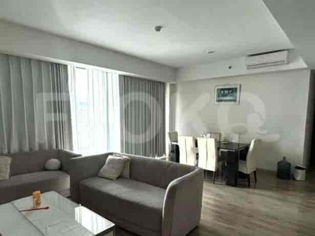 A modern living room featuring a grey sofa, dining table, and large windows with sheer curtains.
