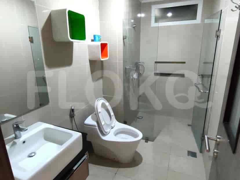 A modern bathroom featuring a toilet, sink, shower and a glass partition.