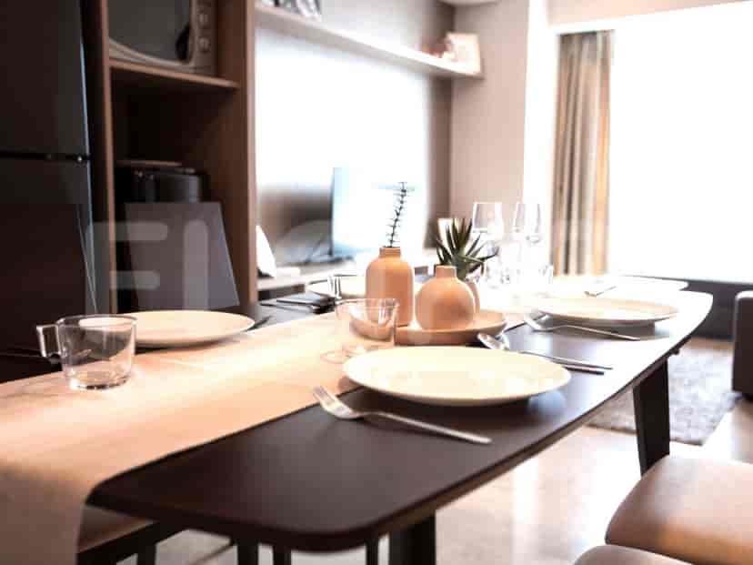A dining area with black table next to a bedroom with white linens.