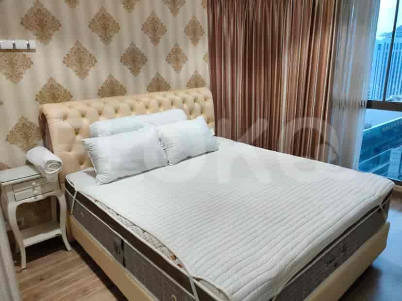 Another bedroom view, featuring a bed with white bedding, bedside table, and window with curtains.