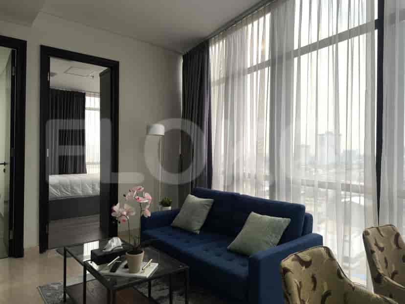 Living room with blue sofa, glass coffee table, and large windows.