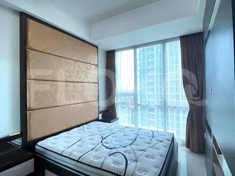 A bedroom with a bed, headboard, and window overlooking the city.