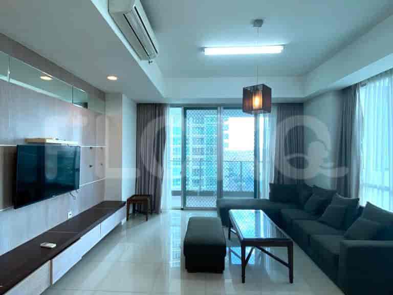 A modern living room with an L-shaped grey sofa, TV, and a view of the city.