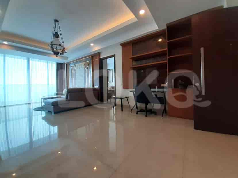 A modern living room with a grey sofa, desk, and bookshelf.
