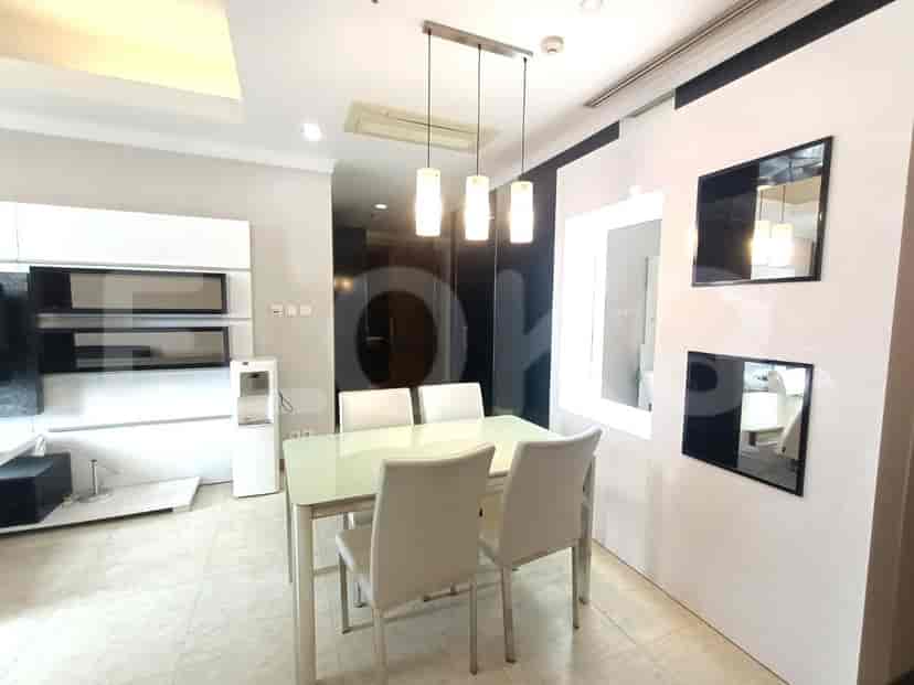 A dining area with a glass table and white chairs.