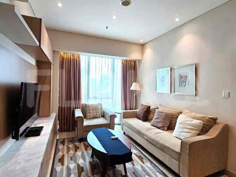 Ruang tamu yang nyaman dengan sofa, kursi, dan pengaturan TV.
