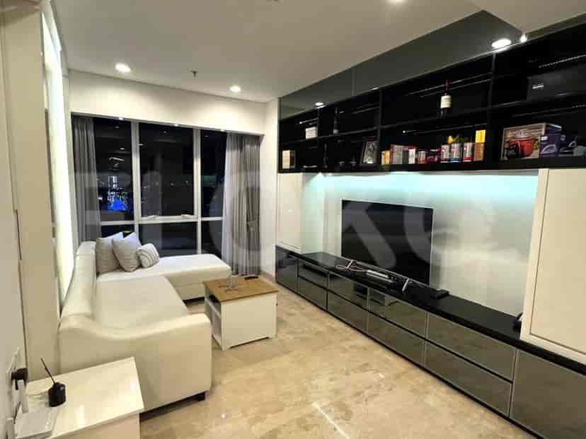 Ruang tamu yang terang dengan sofa berbentuk L berwarna putih, TV, dan pemandangan kota.