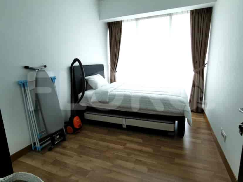 Bedroom with a bed, ironing board, and a vacuum cleaner.