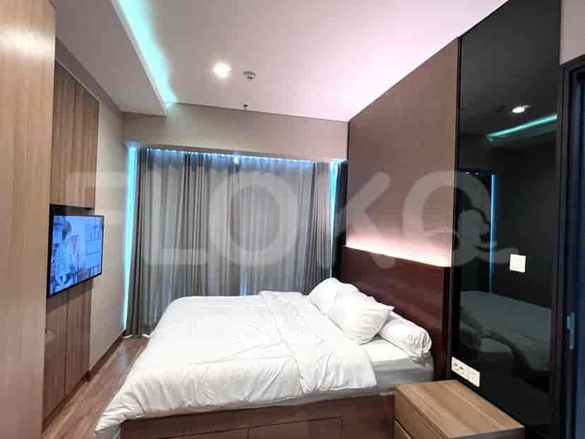 Kamar tidur modern dengan tempat tidur, lemari pakaian built-in, dan TV.