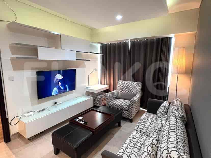 Ruang tamu modern dengan TV, sofa, dan kursi.