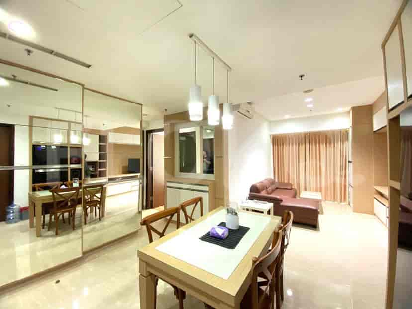 A dining area with a wooden table and chairs, leading into a living space with a sofa and entertainment unit.