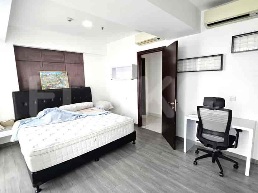 A bedroom with a bed, a desk and door to another room.