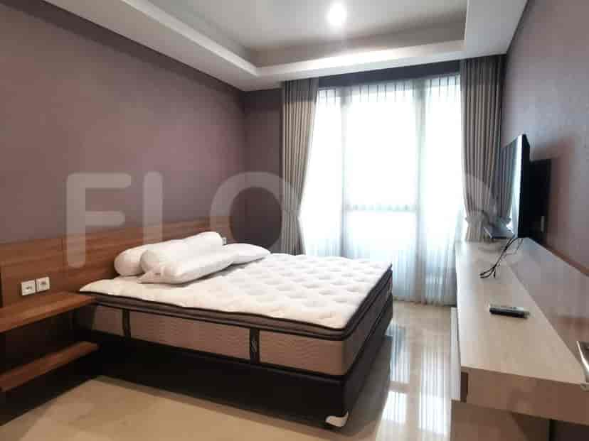 A bedroom with a king-sized bed, large windows, and a modern TV.