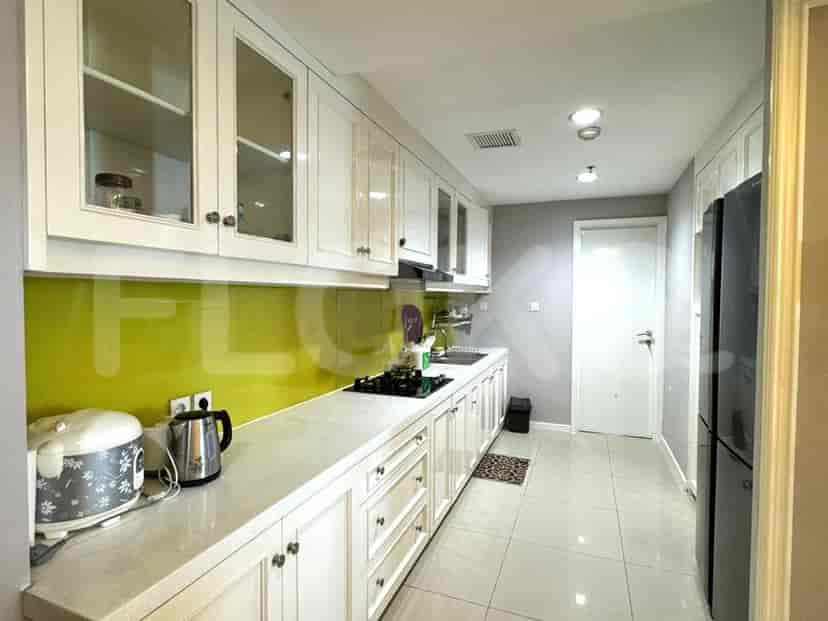 A modern kitchen with white cabinets, a green backsplash, and a black countertop.