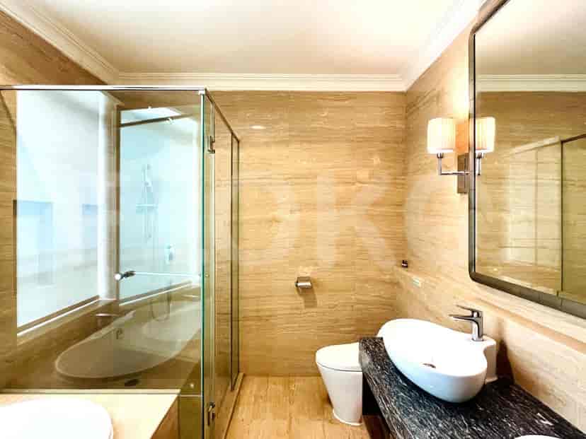 Kamar mandi luas dengan bak mandi dan penutup pancuran kaca.